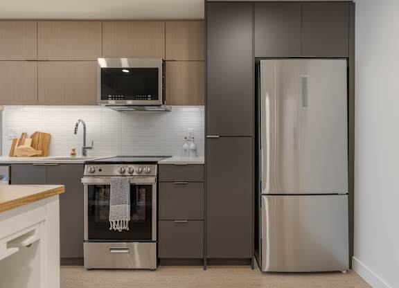 A modern kitchen with a stainless steel refrigerator and oven.