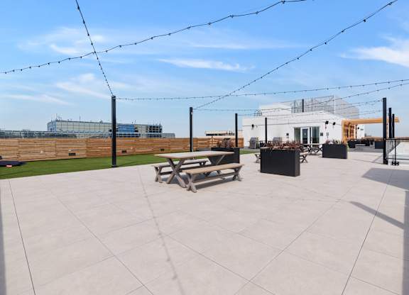 A patio with a table and chairs is surrounded by a fence and has a building in the background.