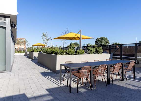 A patio with a table and chairs and umbrellas.