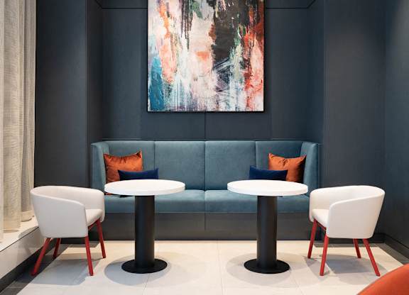A modern living room with a blue couch, two white chairs, and a large abstract painting on the wall.