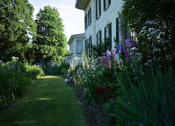 A white house with a garden in front.