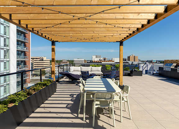 A patio with a table and chairs under a wooden pergola.