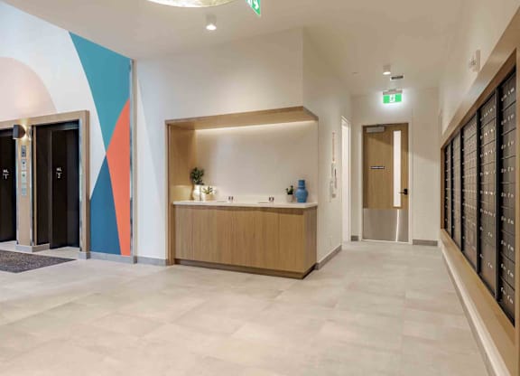 A hallway with a reception desk and a green exit sign.