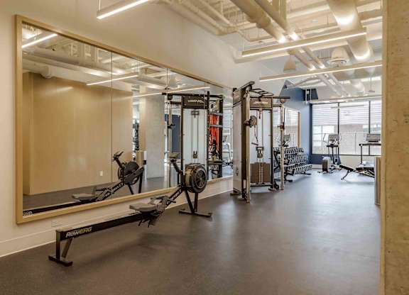 A gym with a mirror, weights, and exercise equipment.