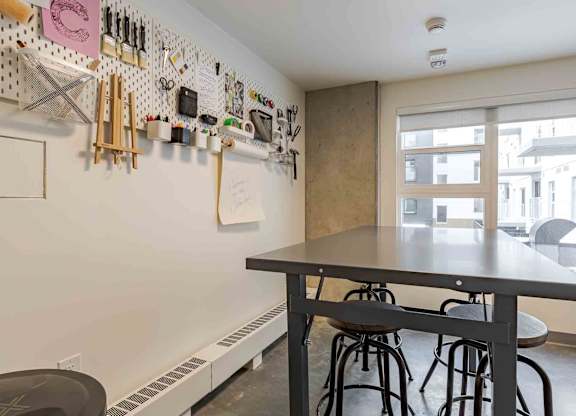 A kitchen with a table and chairs and a wall of utensils.