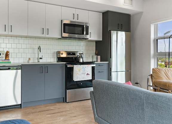 A modern kitchen with a grey couch in front of it.