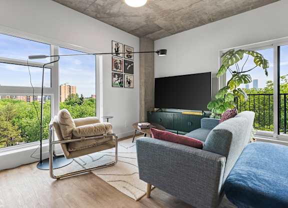 A living room with a grey couch and a chair with a metal frame.