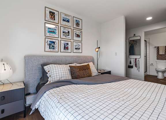 A bedroom with a bed, nightstand, and pictures on the wall.