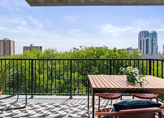 A balcony with a table and chairs overlooking a cityscape.