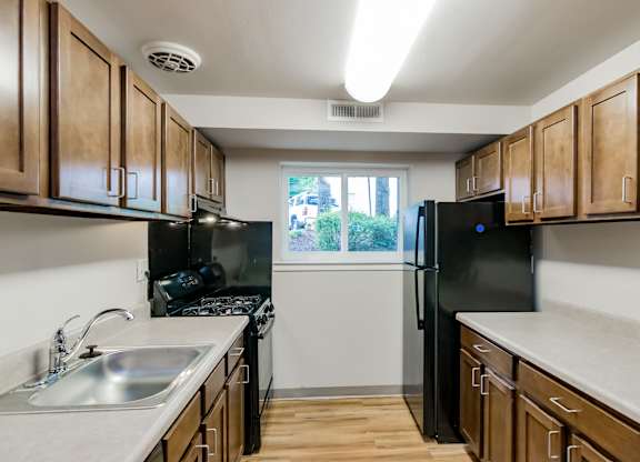 A kitchen with wooden cabinets and black appliances.