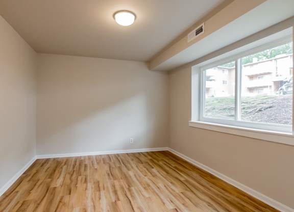 A room with a window and wooden flooring.
