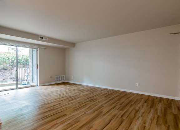 A room with wooden flooring and a sliding glass door.
