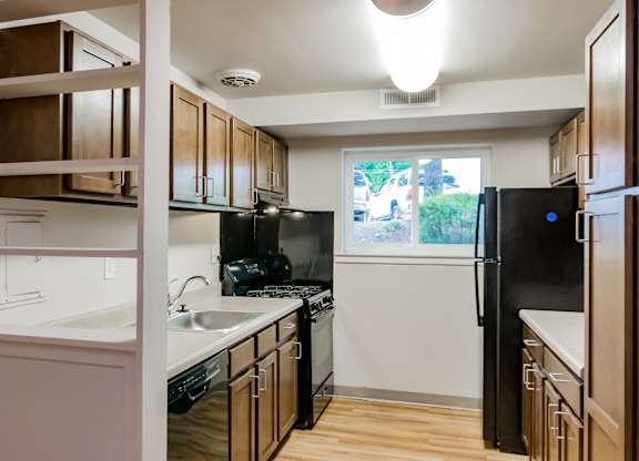 A kitchen with black appliances and wooden cabinets.