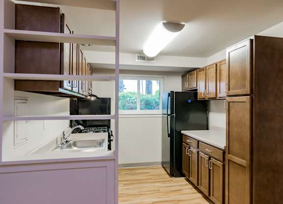 A kitchen with brown cabinets and a black refrigerator.