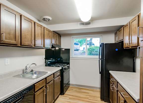 A kitchen with wooden cabinets and black appliances.