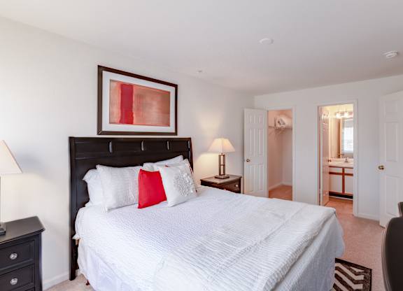 A bedroom with a large bed and a painting above it.
