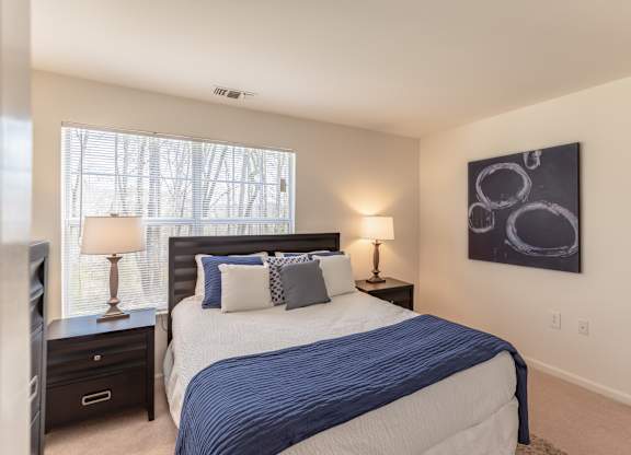 A bedroom with a large bed and a painting on the wall.