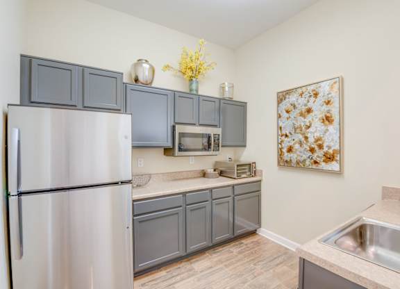 A kitchen with a refrigerator, microwave, and sink.