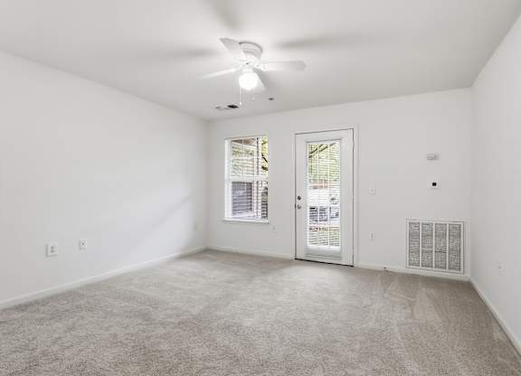 A room with a carpeted floor and a ceiling fan.