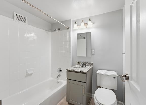 A white toilet sits next to a bathtub in a bathroom.