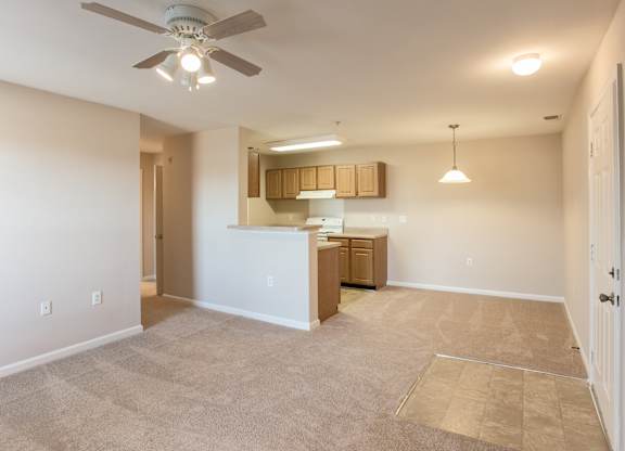 A spacious living room with a ceiling fan and lighting fixtures.