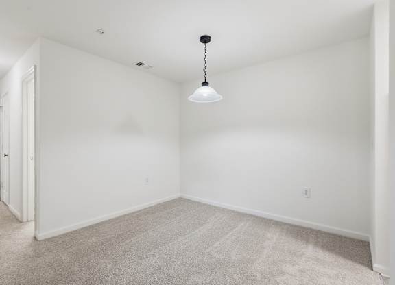 A room with a carpeted floor and a hanging light fixture.