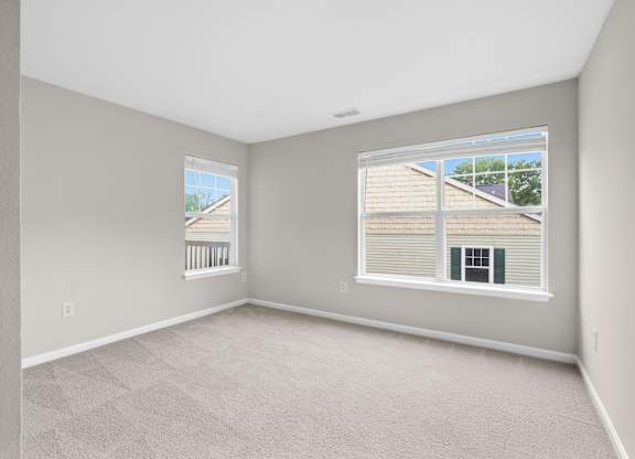 A room with a large window and a view of a house across the way.