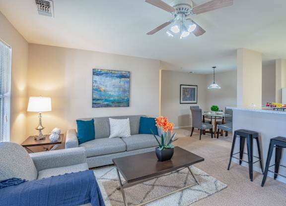 A living room with a grey couch, a coffee table, and a painting on the wall.