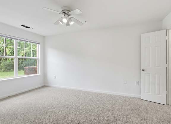 A room with a ceiling fan and a door.