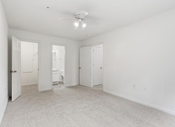 A spacious room with a ceiling fan and carpeted floor.