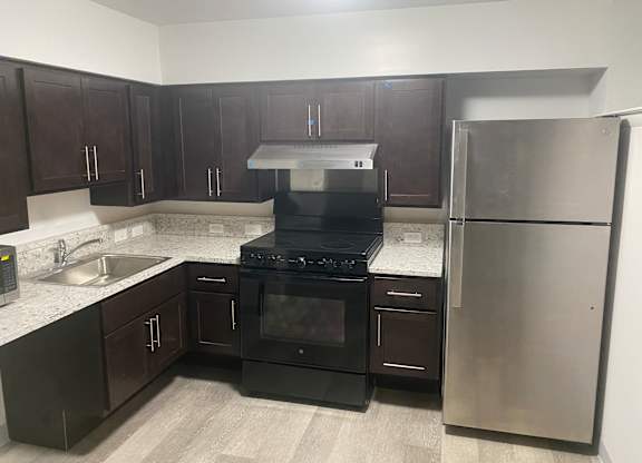 A kitchen with black appliances and brown cabinets.