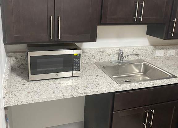 A kitchen with dark brown cabinets and a stainless steel oven.