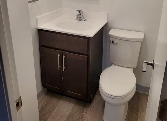 A white sink with a brown cabinet underneath it.