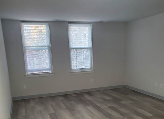 A room with a wooden wall and two windows.