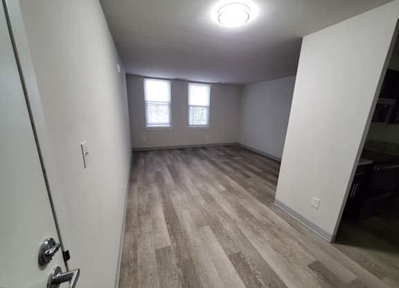 A room with wood flooring and a door on the left.