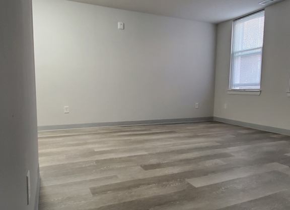 A room with wooden flooring and a window on the wall.