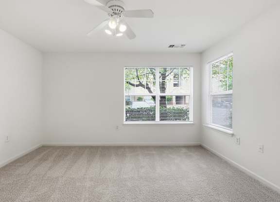 A room with a ceiling fan and a window with blinds.
