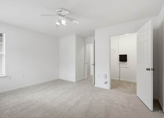 A spacious room with a ceiling fan and carpeted floor.