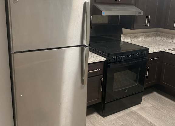A stainless steel refrigerator with a black microwave on top.