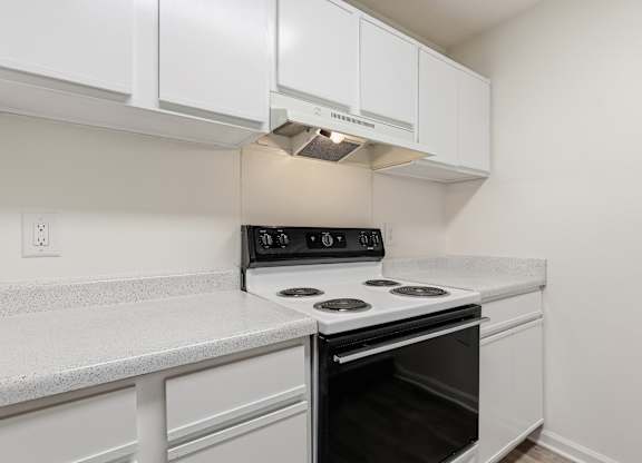 A white kitchen with a black stove top oven.