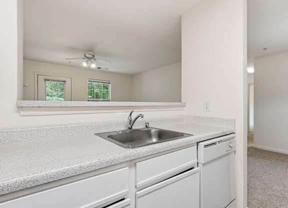 A white kitchen with a sink and a window.