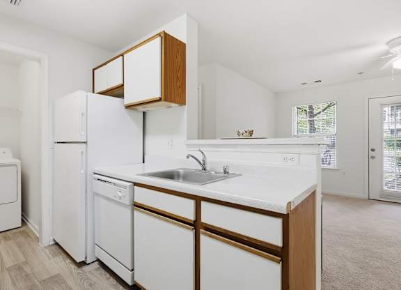 A white kitchen with wooden cabinets and appliances.