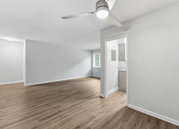 A room with a ceiling fan and wooden flooring.