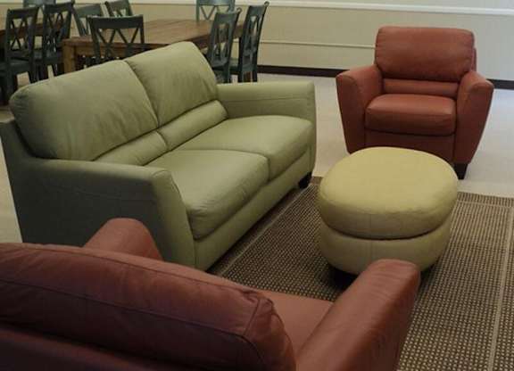 A green couch sits in a room with a brown chair and ottoman.