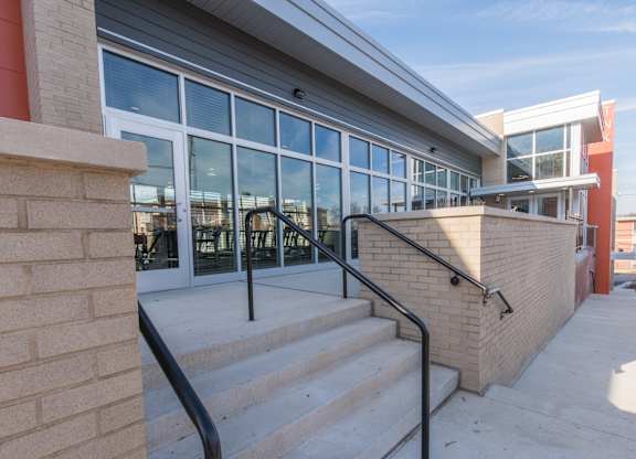 A building with a staircase leading to a glass door entrance.