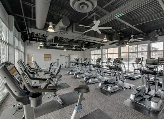A gym with a variety of exercise equipment including treadmills, stationary bikes, and elliptical machines.