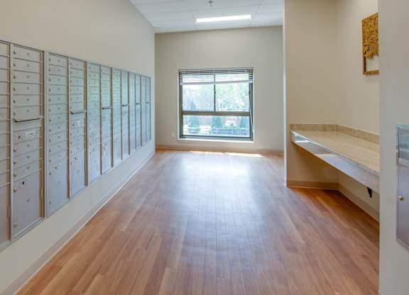 A long hallway with a row of mailboxes on the left and a bench on the right.