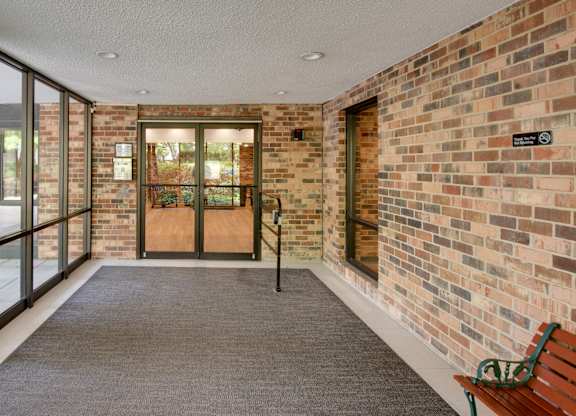A hallway with a brick wall and a bench.