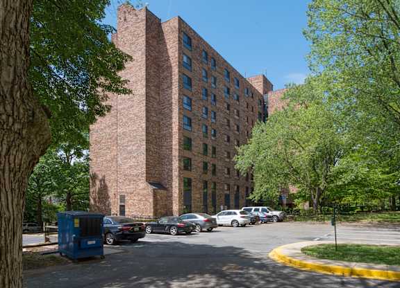 A large brick building is seen in the distance behind a parking lot.