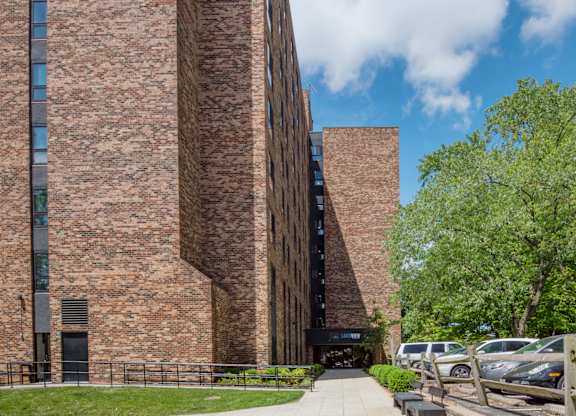 A tall brick building with a parking lot in front.